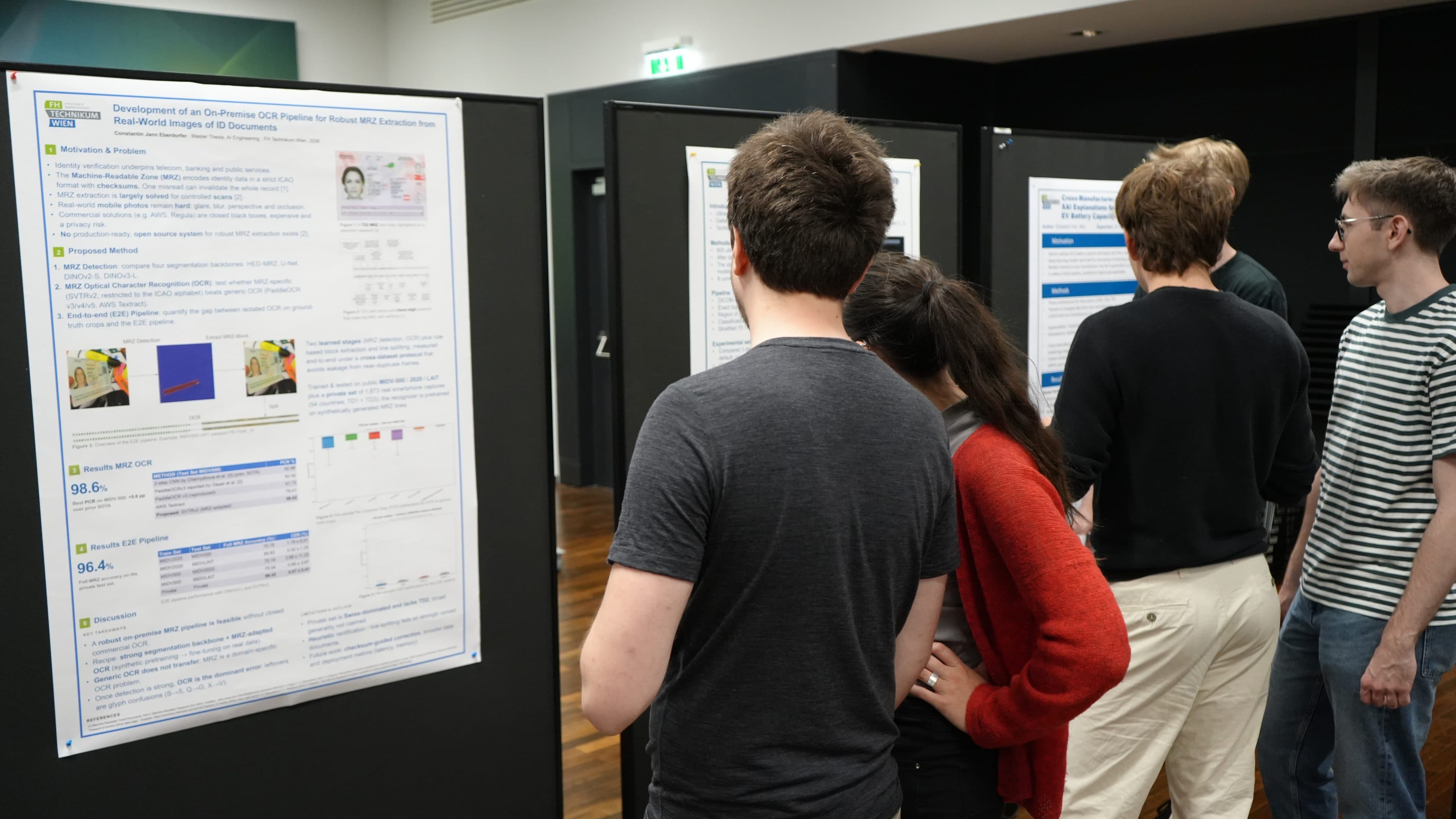 Eine Gruppe von Menschen steht dicht beieinander vor großen Ausstellungstafeln und liest und diskutiert bei einer akademischen oder fachlichen Veranstaltung in einem Saal wissenschaftliche Forschungsplakate.