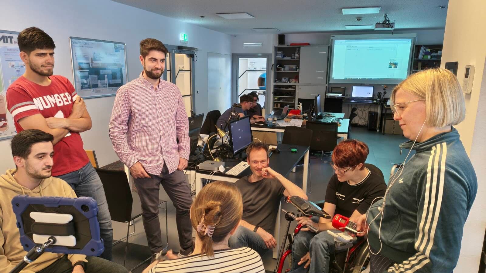 The foto depicts the recording session for Austrian broadcast 'Ö1 digital leben' and shows students, the co-designer and one person from Ö1 holding a microphone.