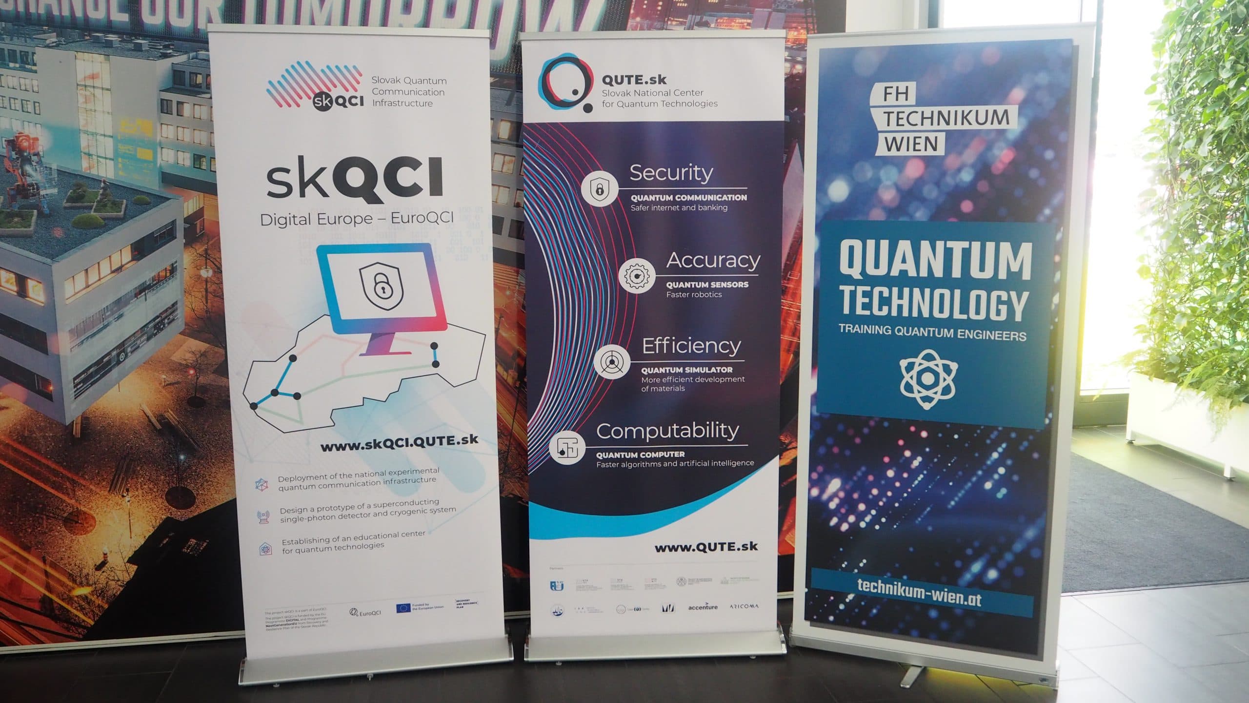 Drei Standbanner, die für Programme im Bereich Quantentechnologie und -technik werben. Jedes Banner zeigt Logos, Texte und Grafiken zu den Themen Quantensicherheit, Genauigkeit, Effizienz und Bildungsinitiativen.