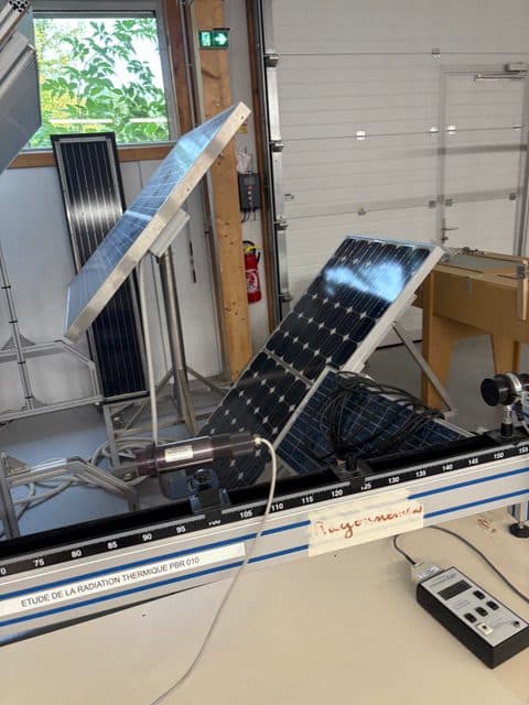 Zwei Solarpaneele sind in einem Raum schräg aufgestellt, auf Ständern mit Messgeräten in der Nähe. Die Geräte scheinen für die Untersuchung der Sonnenstrahlung oder für Experimente mit Wärmestrahlung verwendet zu werden.
