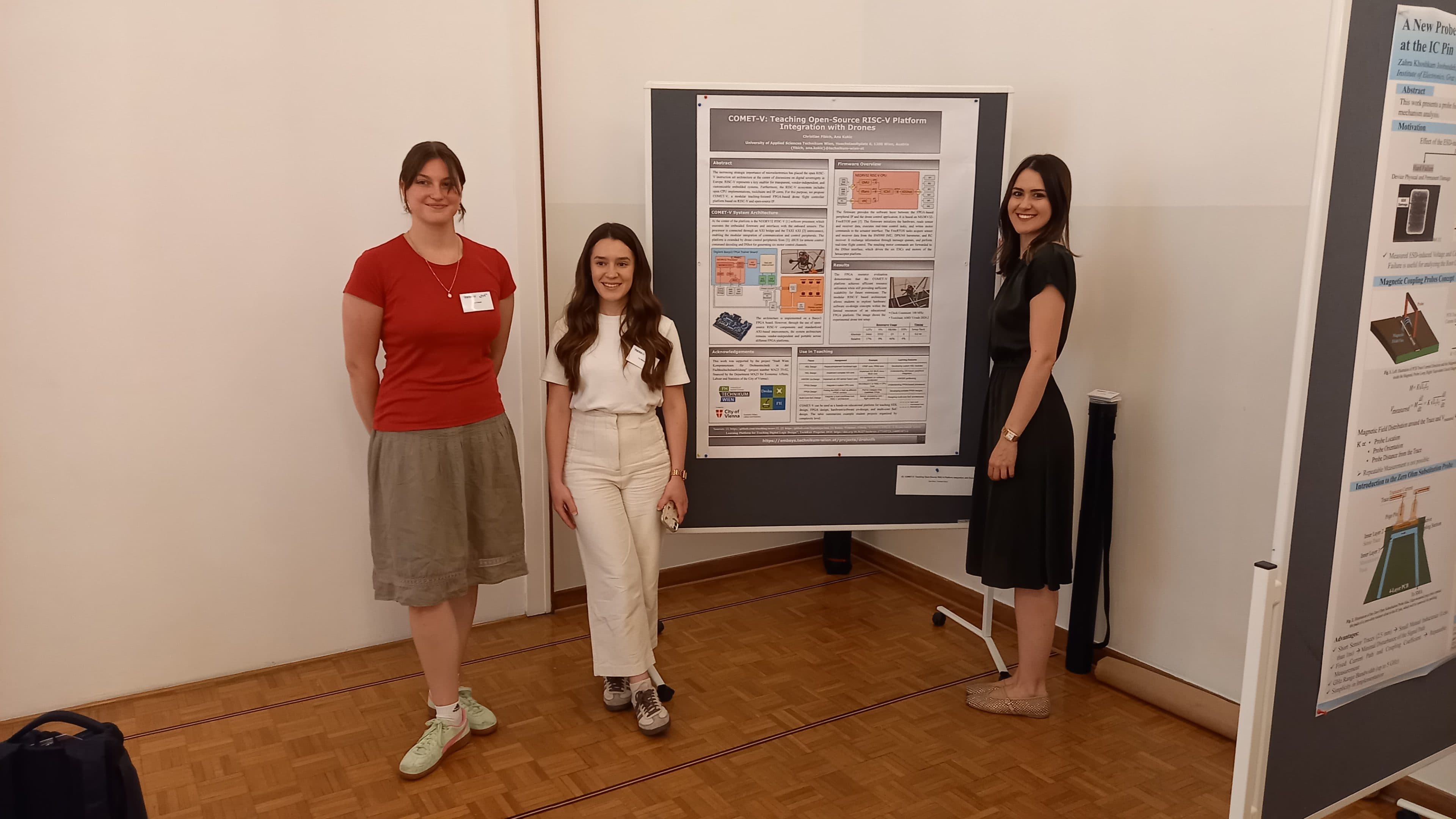 Drei Frauen stehen auf einer Konferenz neben einem Forschungsplakat und lächeln. Zwei stehen links, eine rechts; alle tragen Namensschilder. Die Szene scheint in einem Innenraum mit Parkettboden und weißen Wänden zu spielen.