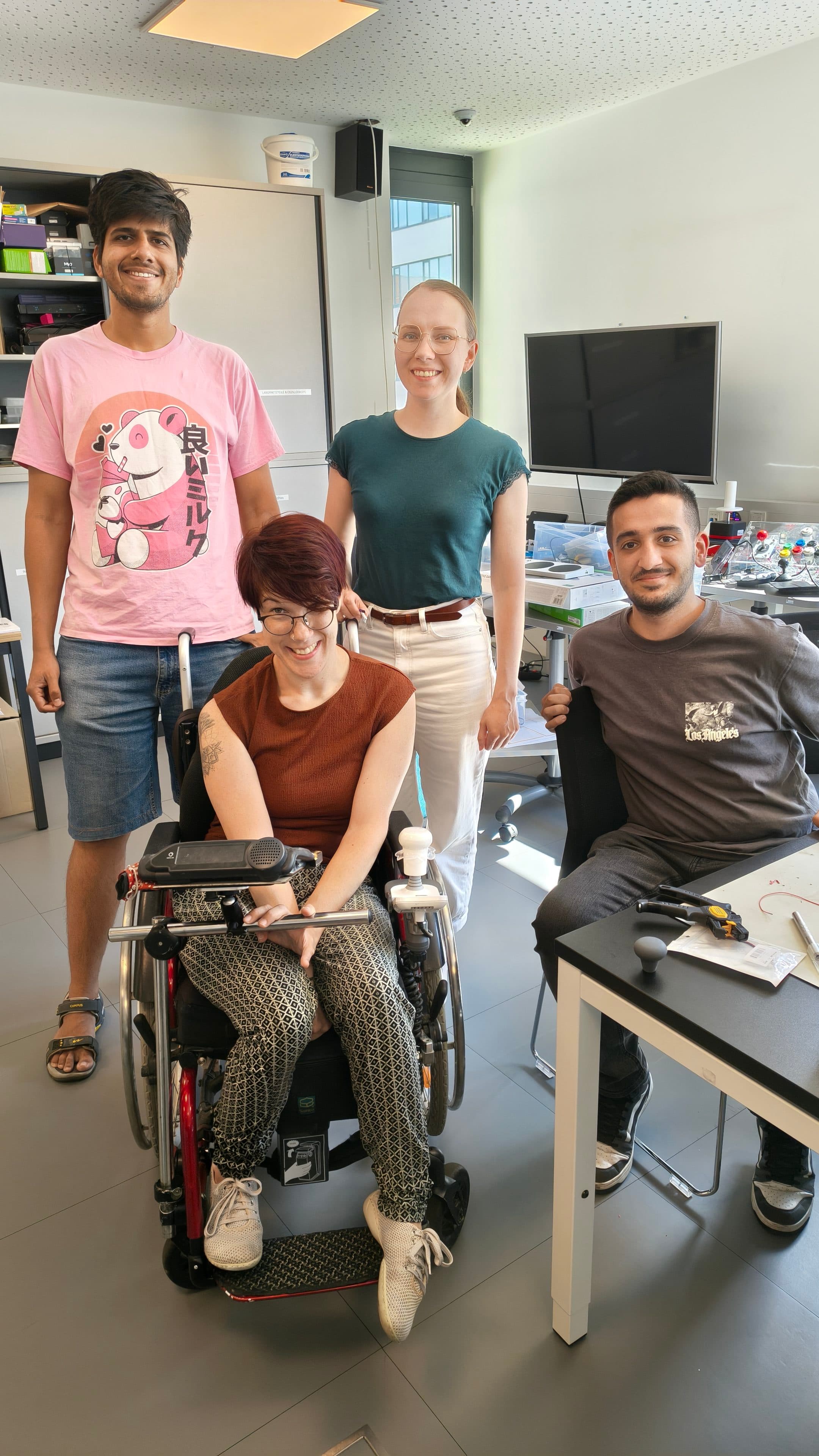 Group picture of team CustomGameStation with Natascha in the middle showing the adapted wheel chair joystick for gaming.