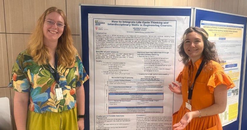 Zwei Frauen stehen lächelnd neben einem großen wissenschaftlichen Poster zum Thema Ingenieurausbildung mit dem Titel Wie lässt sich das Lebenszyklusdenken und interdisziplinäre Kompetenzen in Ingenieurstudiengänge integrieren? auf einer Konferenz oder Veranstaltung.