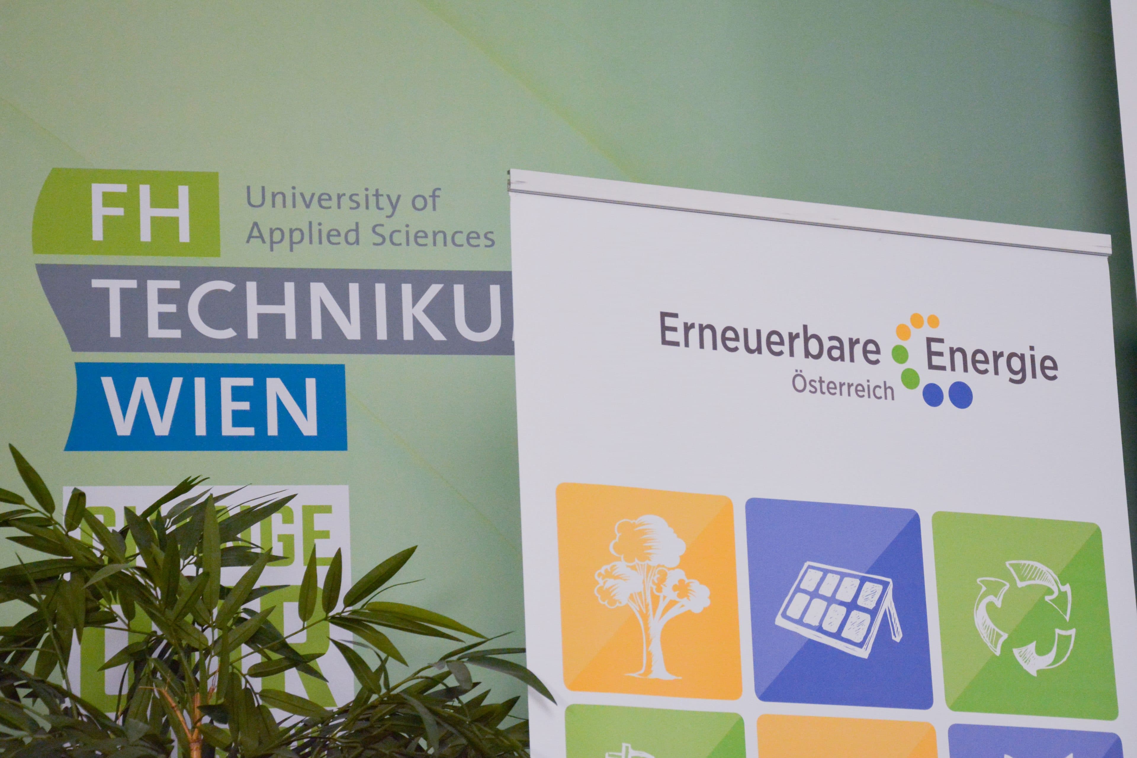 Banner für die Fachhochschule Technikum Wien und Erneuerbare Energie Österreich mit Symbolen für Biomasse, Solarenergie und Recycling. Im Vordergrund ist eine grüne Pflanze zu sehen.