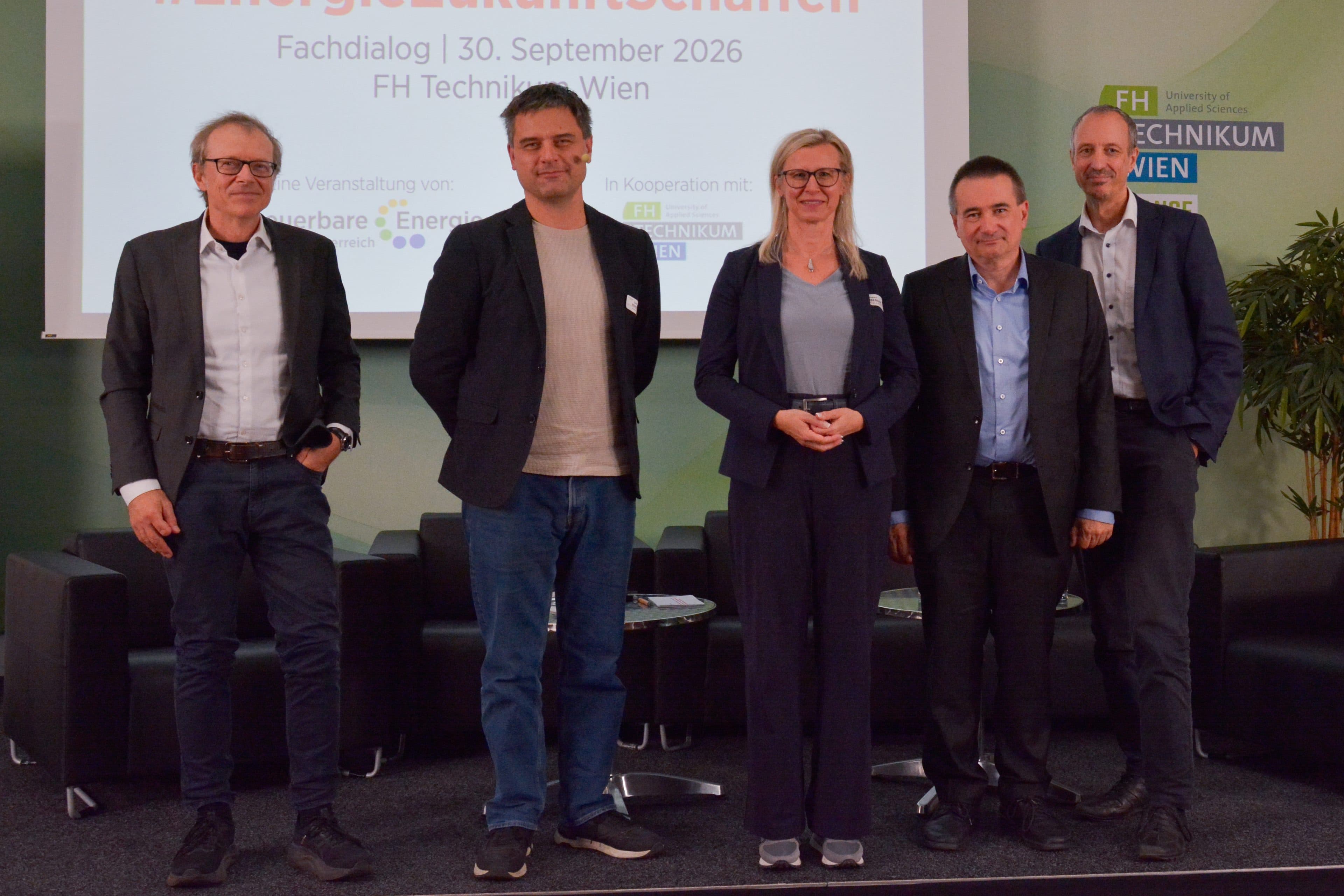 Fünf Personen stehen in einer Reihe vor einer Konferenztafel mit der Aufschrift EnergieZukunftschancen.