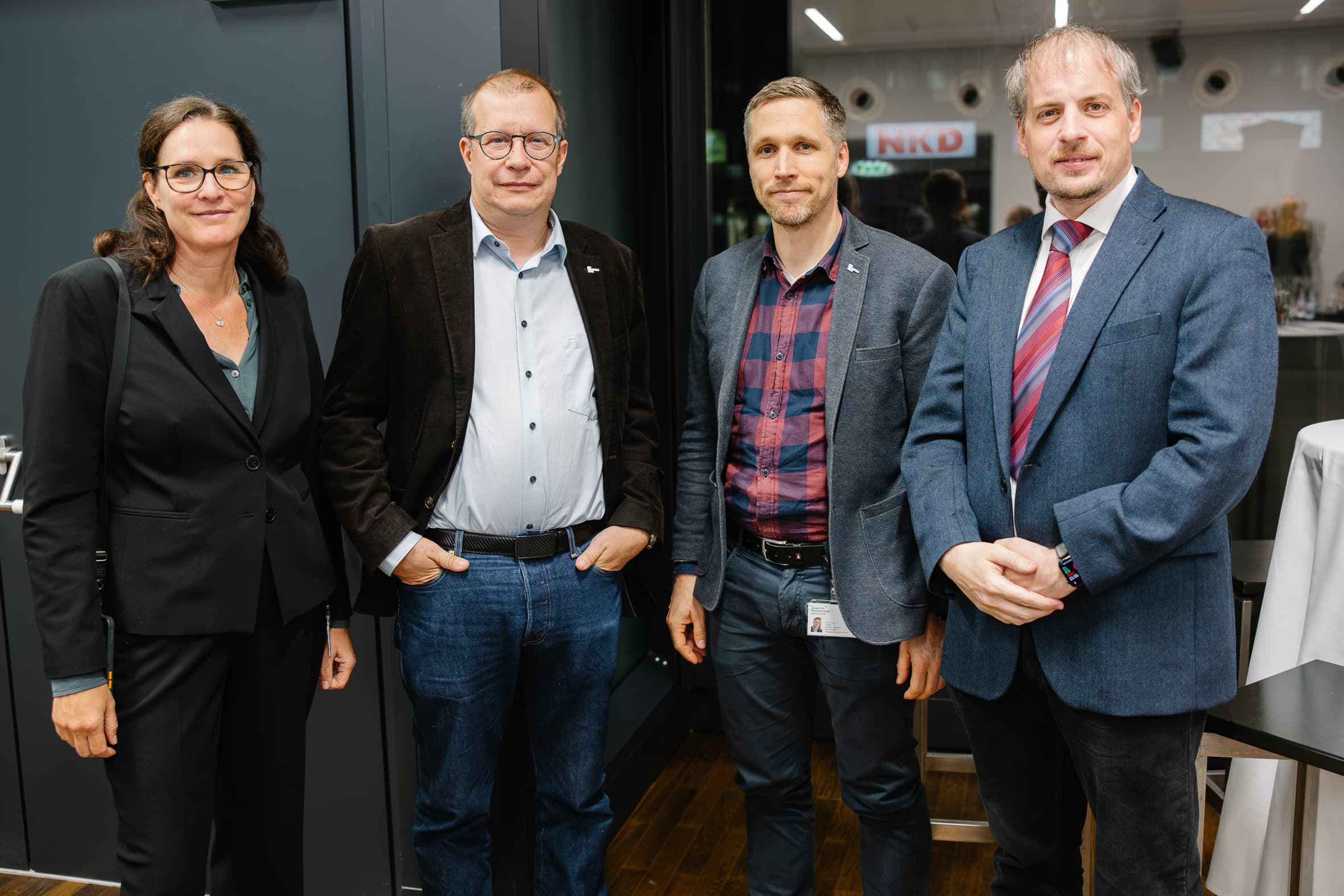 Vier Berufskollegen, die für ein Gruppenfoto zusammenstehen.