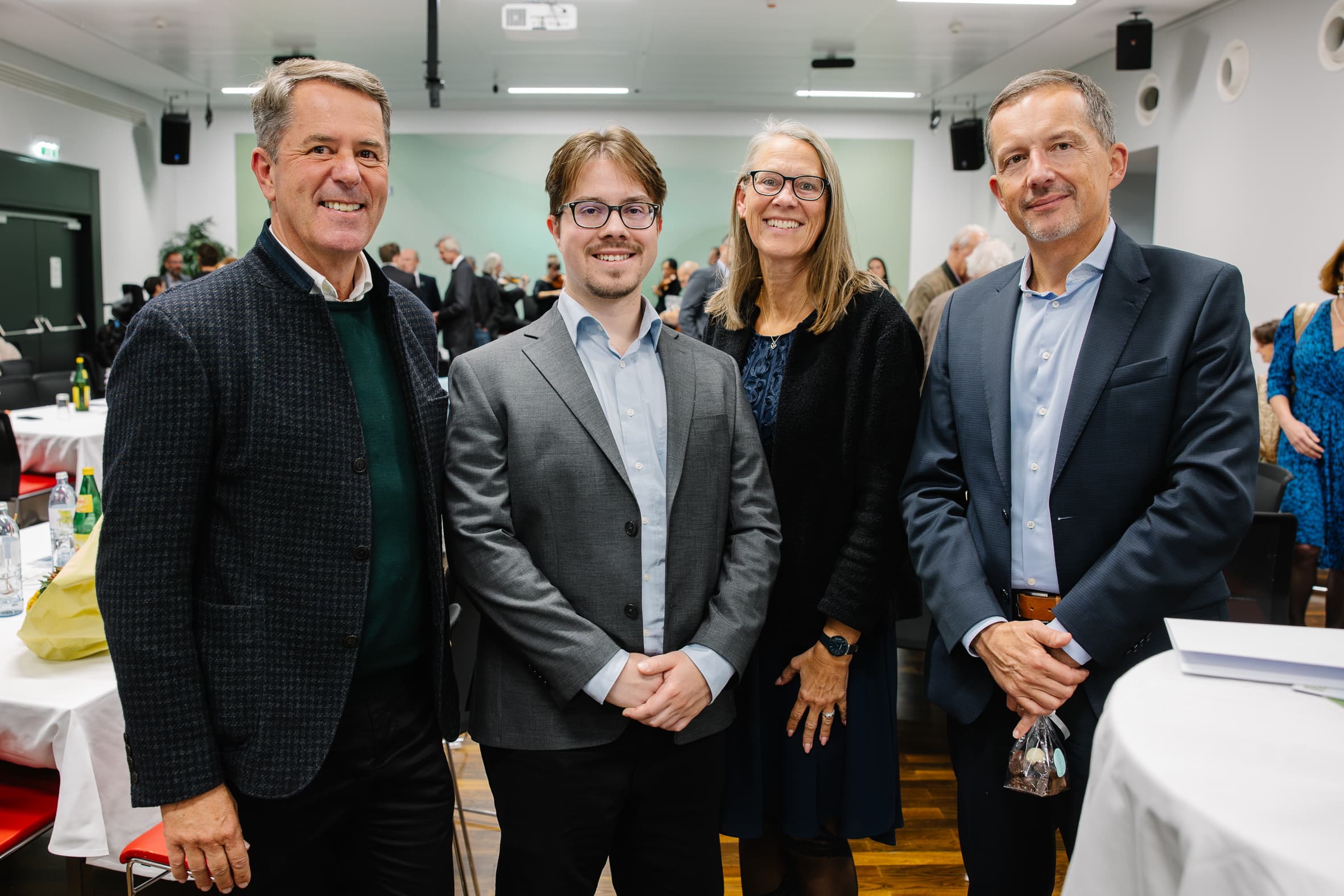 Vier Personen stehen gemeinsam in einem Konferenzraum bei einer Fachveranstaltung.
