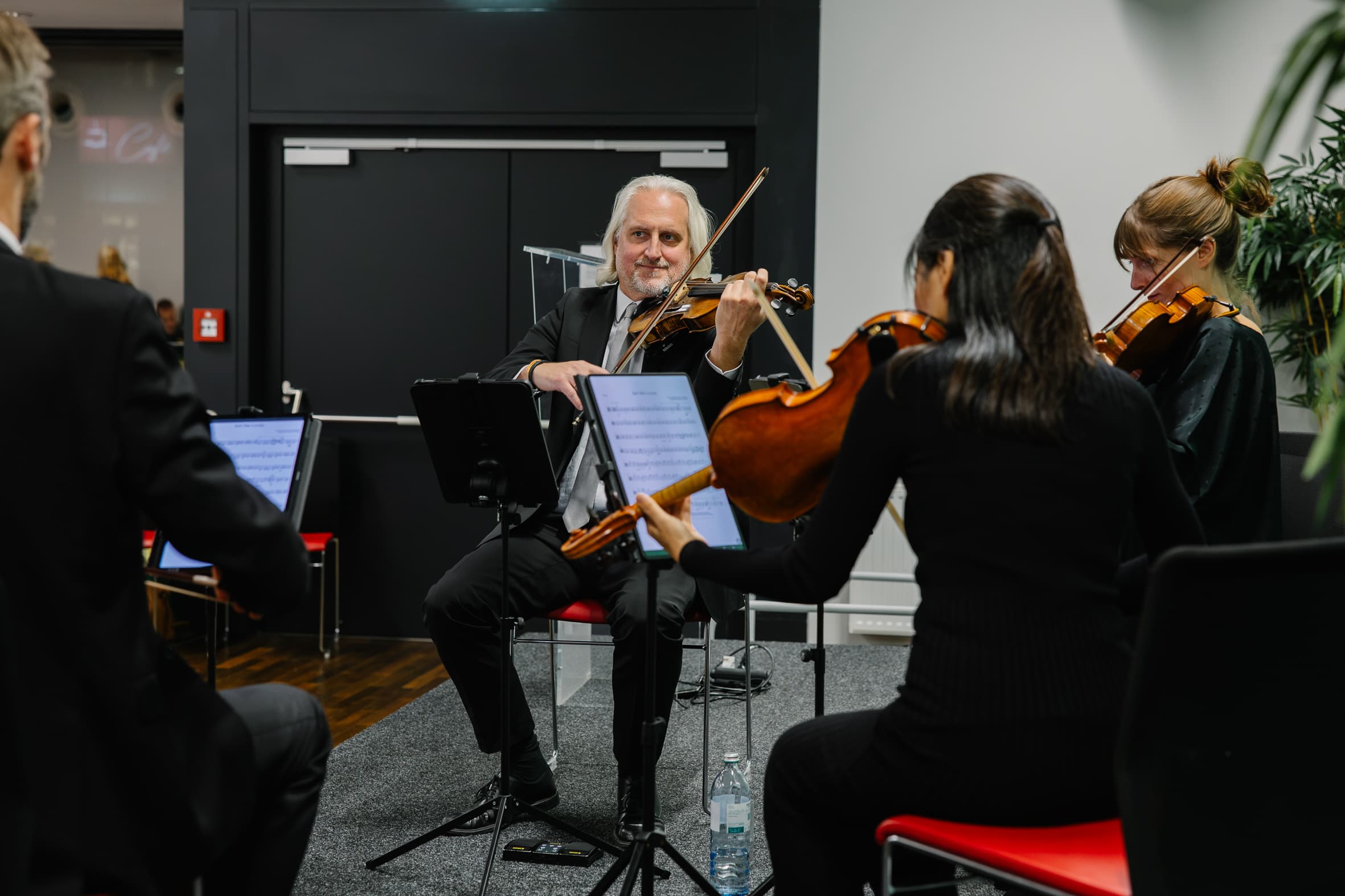 Ein Streichquartett spielt, wobei ein Geiger in der Mitte in die Kamera blickt.